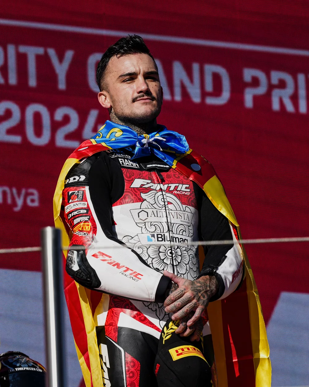 Arón Canet, piloto profesional de motociclismo y paciente de AP, en el podio con el mono de competición
